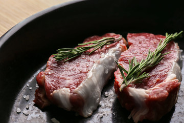 Raw steaks with rosemary and salt, closeup