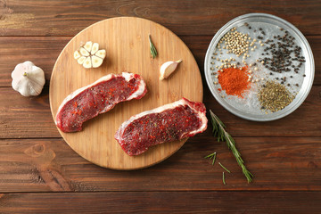 Juicy raw steaks and spices on wooden table