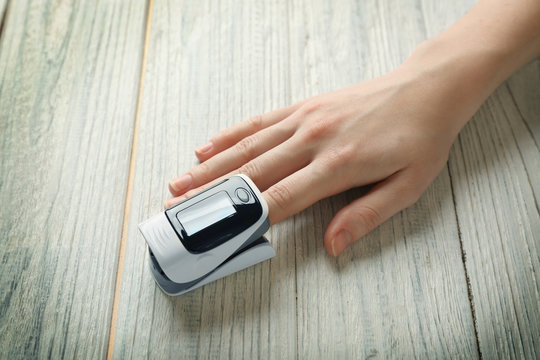 Female Hand With Heart Rate Monitor On Wooden Background