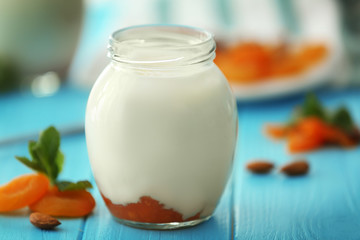 Glass jar with delicious yogurt on wooden table