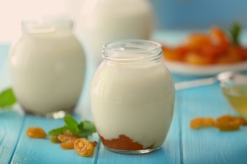 Glass jar with delicious yogurt on wooden table