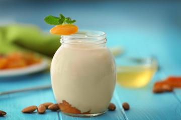 Glass jar with delicious yogurt on wooden table