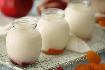 Glass jars with delicious yogurt on tray