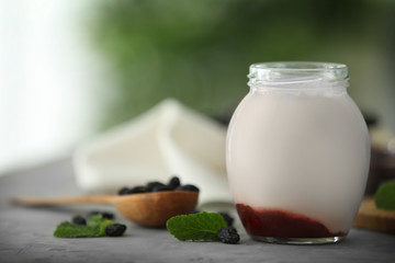 Glass jar with delicious yogurt on table