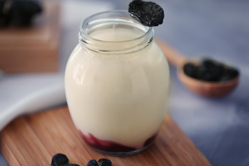 Glass jar with delicious yogurt on board