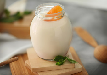 Glass jar with delicious yogurt on board