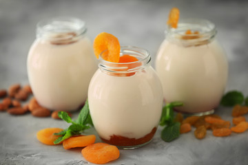 Glass jars with delicious yogurt on grey background