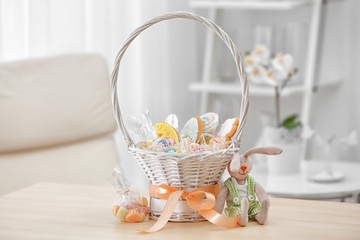 Fototapeta na wymiar Delicious gifts in Easter basket on blurred background