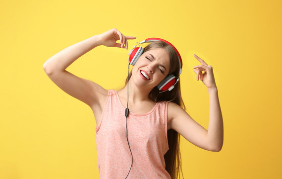 Beautiful young woman listening to music on color background