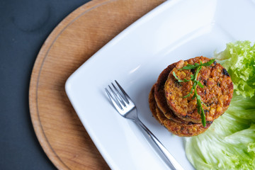 Fried vegetable patties on a plate. Yummy patties made of potatoes, green peas, carrot and green beans and garnished with fresh green onion. Veggie lunch or dinner idea.