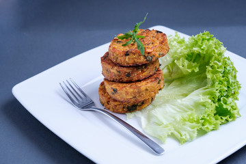 Fried vegetable patties on a plate. Yummy patties made of potatoes, green peas, carrot and green beans and garnished with fresh green onion. Veggie lunch or dinner idea.