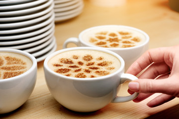 A lot of cups of coffee and a plate with a fire. Cappuccino coffee. A cup of latte, cappuccino or espresso coffee with milk. Drawing the foam milk on top.