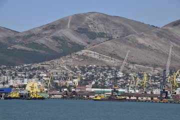 Cargo port with port cranes. Sea bay and mountainous coast.