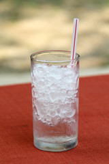 Glass of iced water with plastic straw.