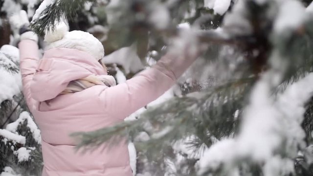 Cheerful active girl enjoys dancing in the winter forest among the spruce trees slow mo