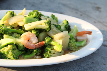 Thai food, stir-fried broccoli with shrimp on white plate.