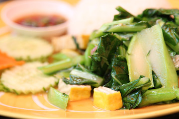 Thai food, stir-fried kale with rice on yellow plate.