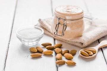 body scrub with almonds for body care on light table background