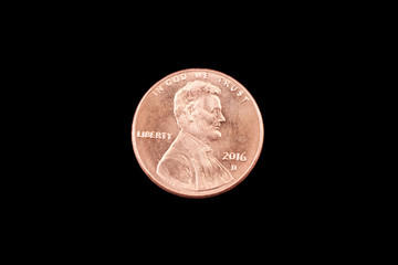 A close up image of an American one cent coin on a black background