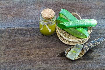 Fresh aloe vera gel on wooden  spoon with aloe  vera essential oil   on wooden table
