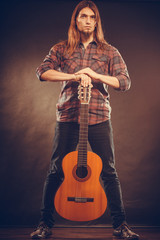 Young man is standing and holding his guitar.