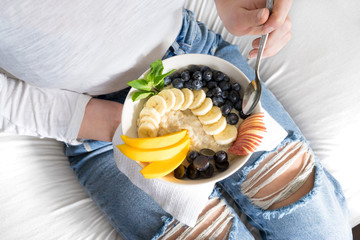 Eating healthy breakfast bowl porridge oats cooked granola fresh and dry fruits and honey in blue ceramic bowl clean eating, dieting, detox, vegetarian food concept