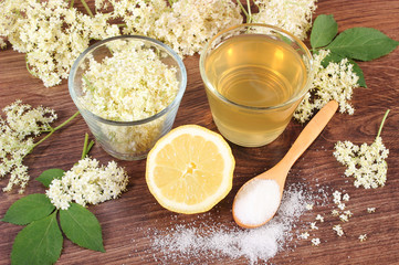 Flowers and juice of elderberry, ingredients for preparing beverage on rustic board