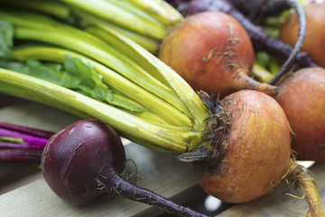 A bunch of golden and purple beets laying on a crate