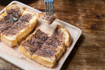 Toast topped with sweetened condensed milk and chocolate on the wooden table