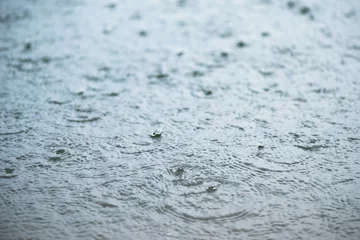 Fototapeten Raindrop on rippling water surface © peangdao