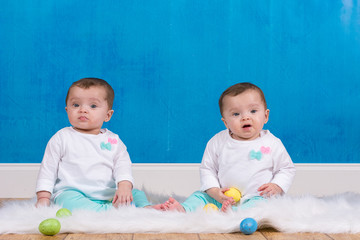 Adorable identical twin girls playing with Easter eggs