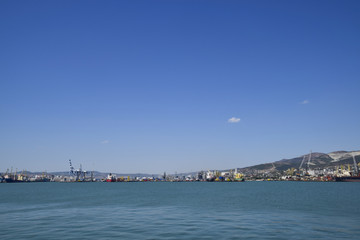 Naklejka premium Cargo port with port cranes. Sea bay and mountainous coast.