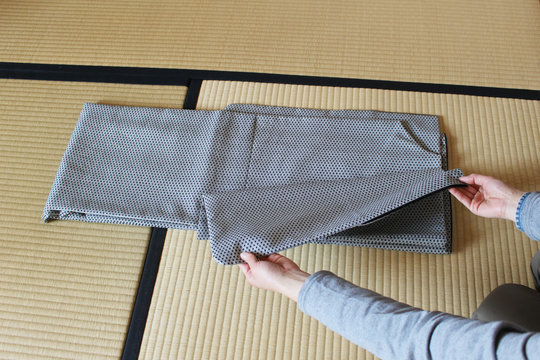 和室の畳の上で着物を丁寧にたたむ女性の所作