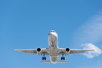 Commercial airplane flying in blue sky, full flap and landing gear extended