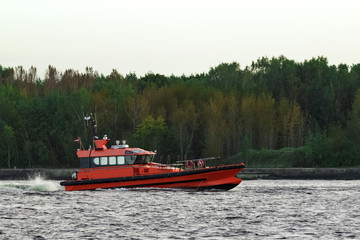 Orange pilot ship sailing on the Daugava river
