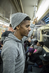 A tired, young african american man rides the NYC subway