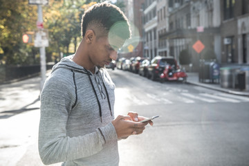 A candid portrait of a young, African American man texting in NYC