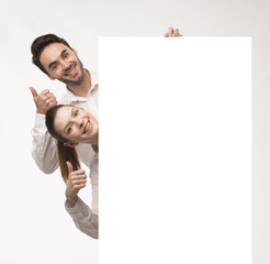 Young happy couple showing presentation pointing on placard over gray background