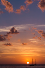 The cloudy sunset and sailing boats. The boats sailing in the ocean in sunset lights. Vertical outdoors shot.