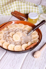 a bowl of porridge with bananas and cinnamon sticks