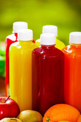 Bottles of delicious organic juice sorrounded by fruits and veggies, beautiful colors, healthy lifestyle concept