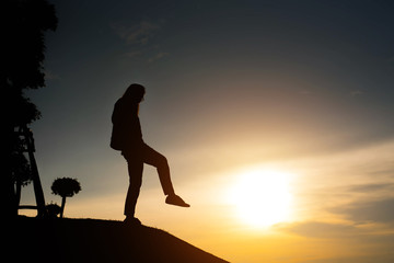 Obraz premium woman silhouette standing looking to sky at sunset
