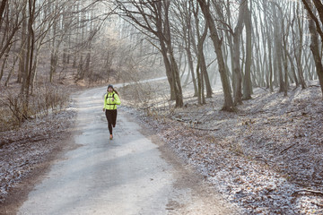 Runner is running through misty morning autumn forest. Sporty young female runner in forest. Running woman. Female runner during outdoor workout in nature. Fitness model outdoors. Weight Loss. 