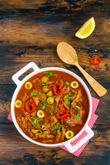 The national dish of Cuba: tender shredded beef stewed with peppers, tomatoes and delicious spices. White casserole on the wooden table, top view. - 141707610