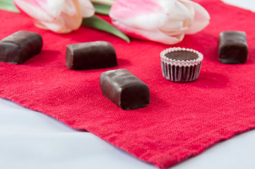 Tulips and chocolate candies on a red background