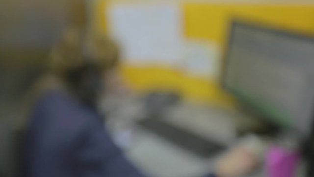 De-focused close-up of a man sitting at his desk screen PC on the table