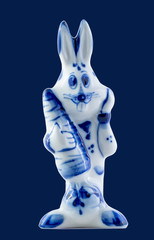 A ceramic rabbit with a carrot in the hands isolated on blue 