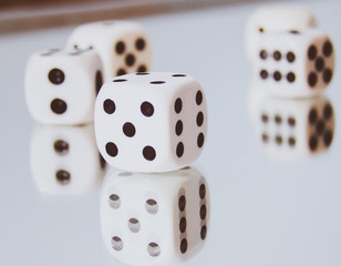White cubic dices lying on a mirror.