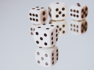 White cubic dices lying on a mirror.