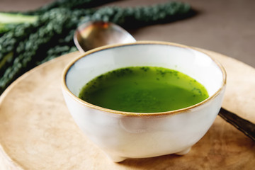 Green Italian soup made from cabbage kale in a white plate. Dark background.